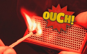 A match strikes off of a matchbox with the word OUCH in a spiked bubble above it.