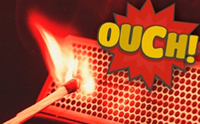 A match strikes off of a matchbox with the word OUCH in a spiked bubble above it.
