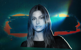 Hailey Bieber has a blue filter over her face and a light shines from behind her.