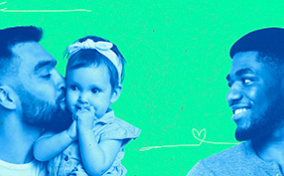 A man kisses a baby he's holding while another man smiles in their direction.