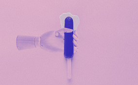 A pink robotic hand holds a blue popsicle on a stick as a clear white liquid puddles at the tip.