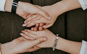 A man and woman hold hands across a wooden table.