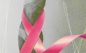 A pink ribbon wraps around a black and white photo of a woman with moles on her torso.