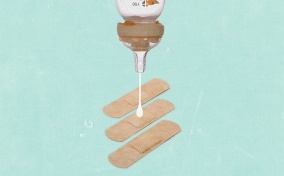 A bottle is upside down dropping breast milk onto a bandaid.