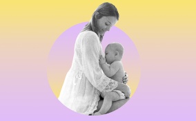 A woman holds her child as it breastfeeds against a yellow and lavender background.