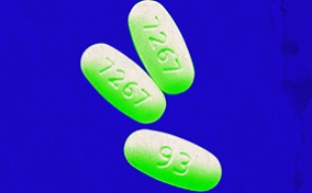Three green and white pills are set on a bright blue background.