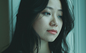 A green-ish filter covers an image of a woman looking out a window.