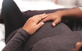 A pregnant person and their partner touch the baby bump.