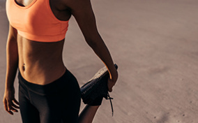 A woman dressed in activewear stretches her leg.