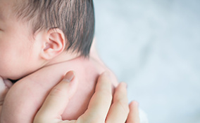 A parent holds their baby against their chest.