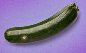 A cucumber with an ingrown hair lays against a purple surface.