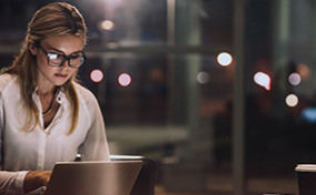 A woman works on her laptop in a coffeeshop at night.