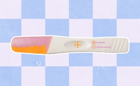A pregnancy test shows a result of pregnant against a blue and white checkered background.