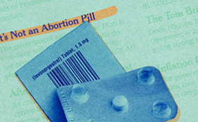 Both sides of plan B pill packet lay against a newspaper with a story about how its not an abortion pill.