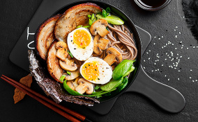 A pan with eggs and vegetables sits on a black counter.