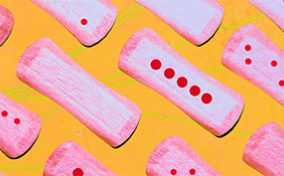 Pink menstrual pads lie opened, next to one another, with red dots on some.