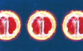 The edges of three open grapefruit halves are in flames against a blue background.
