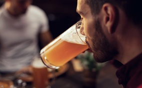 A man is drinking a glass of beer at a restaurant.