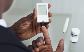A man uses a glucose monitor to test his blood sugar.