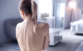 The bare back of a woman displays her spinal cord as she faces away from the camera.