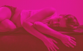 A pink image of a woman laying down in pain