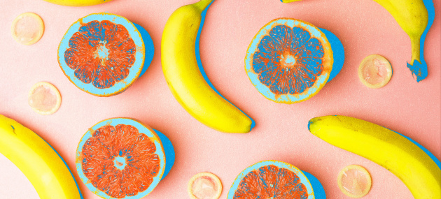 Bananas and open grapefruit are spread amongst condoms.