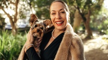 A single woman smiles holding her dog.