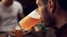 A man is drinking a glass of beer at a restaurant.