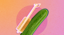 An exfoliation brush rubs against a green cucumber.