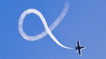 small plane making infinity symbol with chem trail on sky blue background