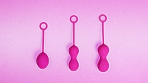 three sizes of pink Kegel balls on pink background