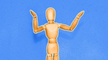 wooden drawing figure with arms out stretched on blue background