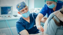 A doctor and a nurse administer an epidural to a pregnant woman during childbirth.