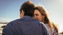 A couple sits with their backs to the camera and one of them looks back over her shoulder.